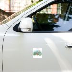 Close-up of a white car door and side mirror with a mountain-themed sticker on the door panel.